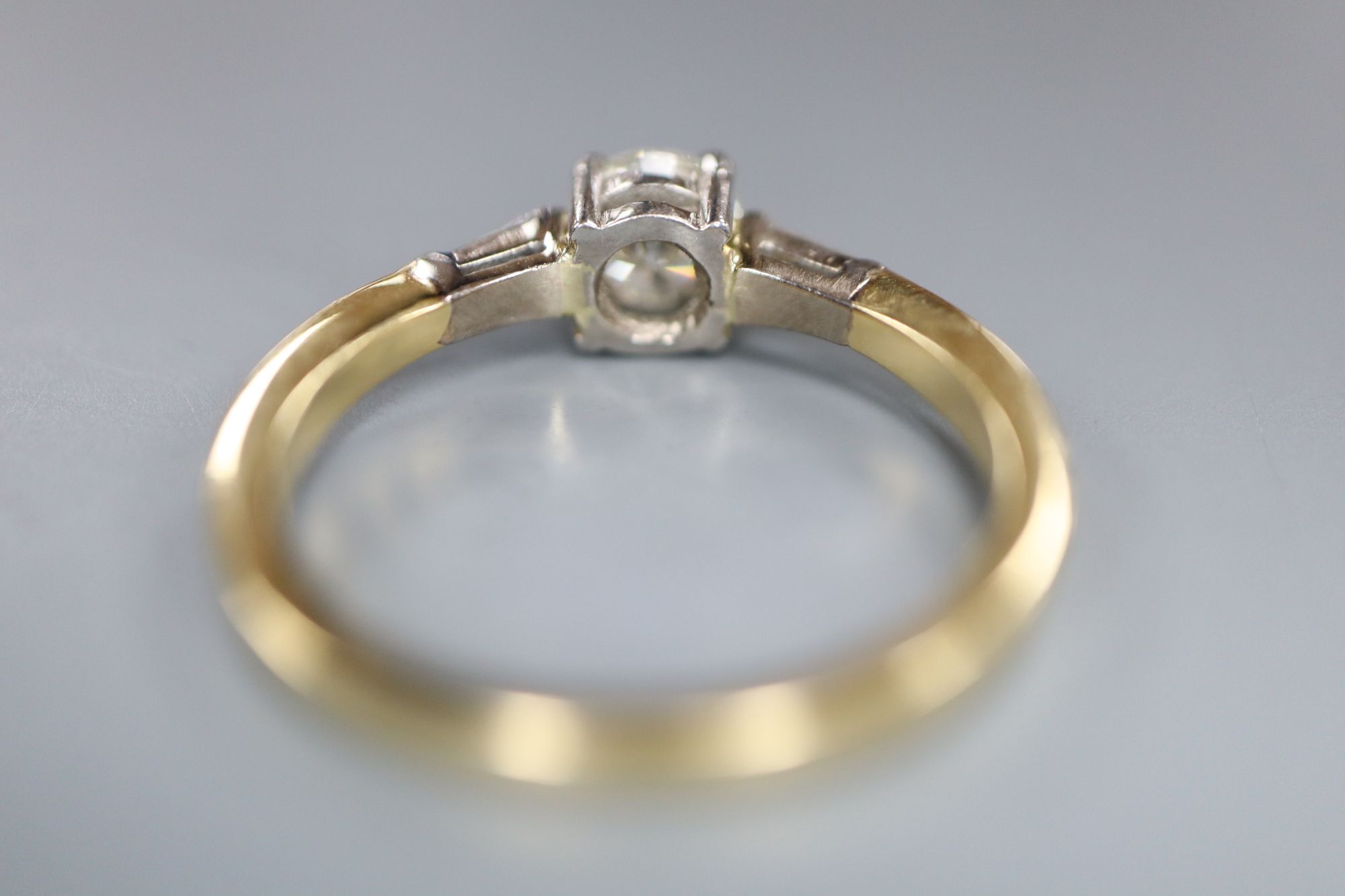 A modern 18ct gold and single stone diamond ring, with trapeze cut diamond set shoulders, size O, gross 3.7 grams,